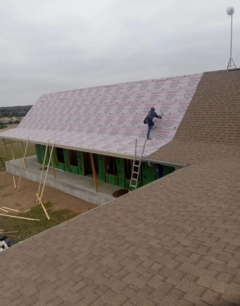 Worker preparing underlayment for a metal roof installation in Atoka